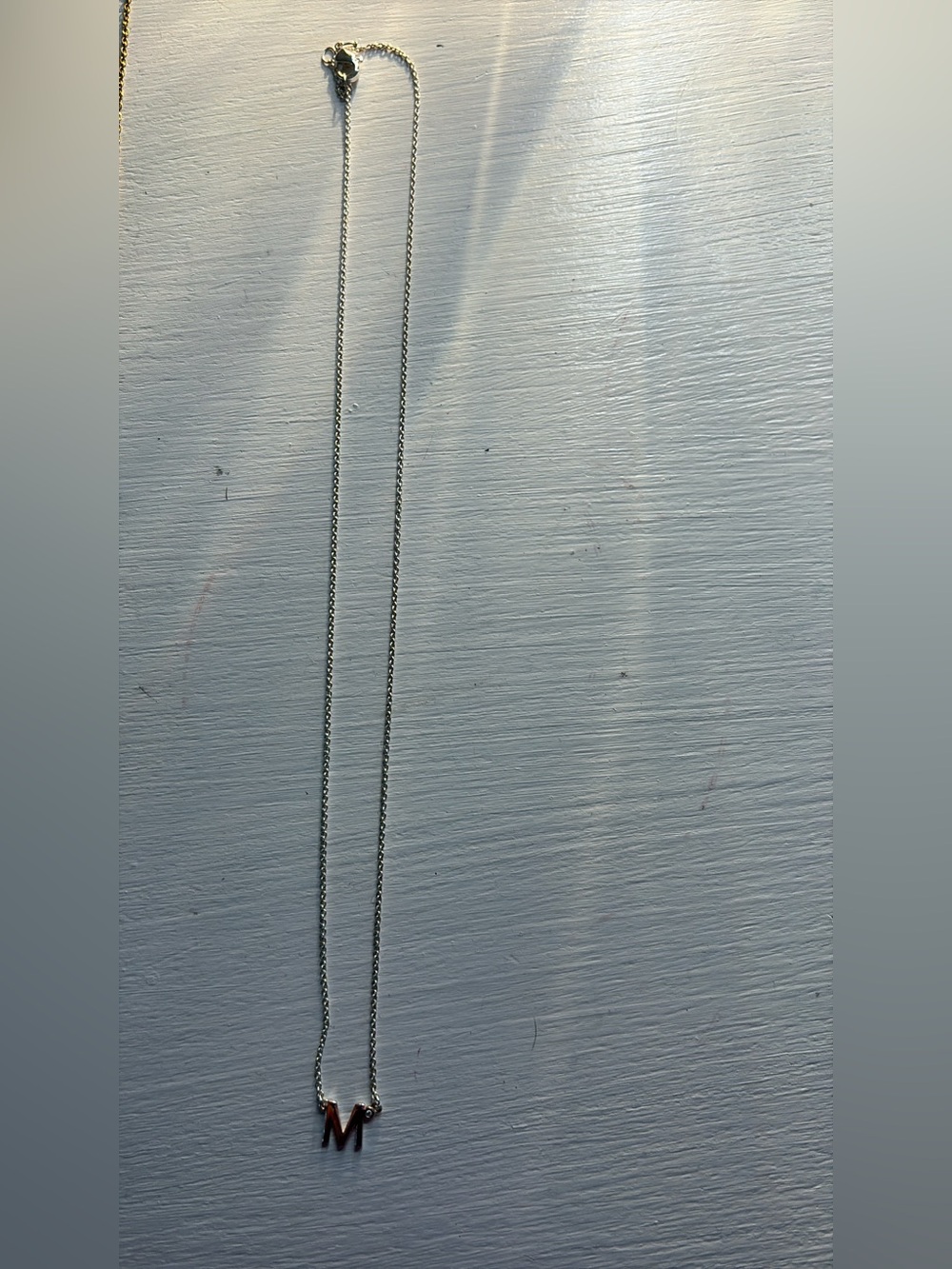 Silver necklace with “M” on it